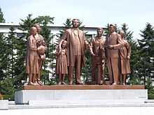 Bronze statue of Kim Il-sung and six other people with camera, a flower basket and a notebook.
