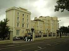 Photograph of front of Georgian-style white/cream Queen's Hotel building.