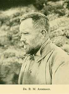 Profile photograph of a man apparently in his thirties, with short dark hair, a neatly trimmed full beard, heavy eyebrows and a high round forehead. He is dressed for outdoor work in cool weather, and is photographed outdoors squinting into the distance.