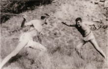 Sepia-toned photograph of two teenagers posing as if fighting, one on the left holding a stick as a spear.