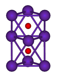  The ball-and-stick diagram shows two regular octahedra which are connected to each other by one face. All nine vertices of the structure are purple spheres representing rubidium, and at the centre of each octahedron is a small red sphere representing oxygen.