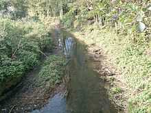 Small water-filled ditch between grassy banks.