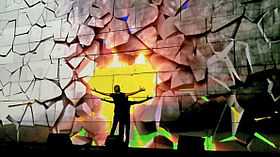 In this scene, Waters punches the wall, while the projections simulate the wall crumbling as a result, revealing a bright sunset behind