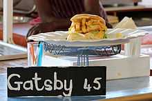 A personal-sized Gatsby sandwich prepared with calamari and chips, being sold at a food stall for $45 South African rand (approximately $3.75 in United States dollars)