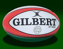 An oval shaped synthetic ball, white in colour with red trim, adorned with the manufacturers name.