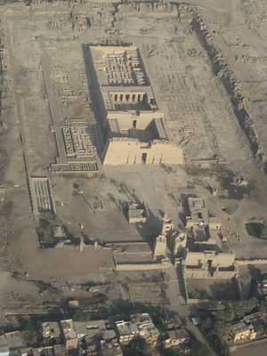 Rectangular stone building from above, with courtyards and pylons at the front and the remains of walls at the back. A rectangular wall and the foundations of other buildings surround the main building.