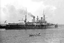 A black and white picture of a large ship with a small, lifeboat-sized ship in front of it.