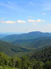 Green tree covered mountains turn blue as the progress toward the horizon.