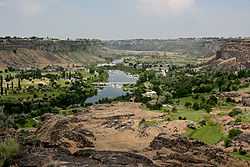 A canyon with land covered in a mix of grass and sand