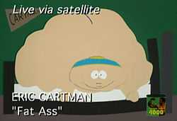 A crudely animated cartoon image of an enormously obese young naked boy lies on a bed and stares straight ahead. The image is meant to resemble a live television broadcast image, as indicated by the text "Live via satellite" at the top of the screen, and the words "ERIC CARTMAN, Fat Ass" on the bottom.