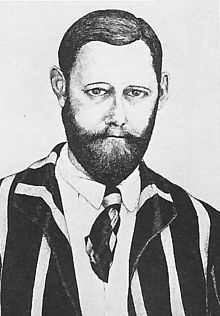 head and shoulders portrait of a middle-aged man with a beard wearing a striped jacket