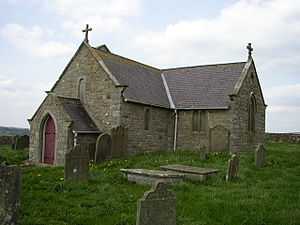 A small stone church seen from the southwest with a south transept as large as the nave