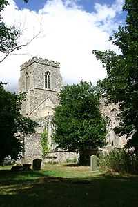 A flint church seen between trees, the body ruined and roofless, the tower with a battlemented parapet