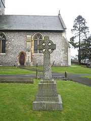 Stone Celtic cross in front of a church