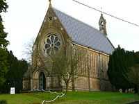 Tall stone-built church with rose window and bellcote