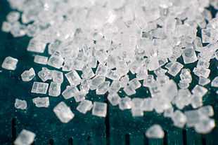 Photograph showing crystals of refined sucrose.  A millimetre ruler down the picture shows the scale of the grains is between 0.5 and 1 millimetre.