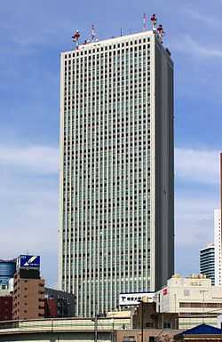 Ground-level view of a gray, rectangular high-rise lined with columns of windows