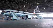 Side view of a parked Delta Air Lines twin-engine jet in hangar, with stairs mounted next to the aircraft's forward door.