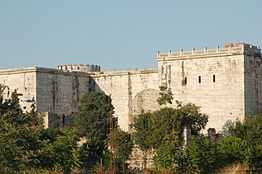 Photo of a marble-covered gate complex with two square projecting towers and a walled-in gate