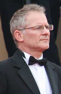 Portrait photo of a man with salt-and-pepper hair and glasses in a tuxedo with a bow tie.
