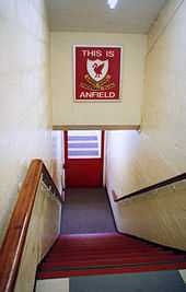 steps leading down to  tunnel, above the tunnel is a sign with This Is A Field in white letters on a red background, with a crest on it