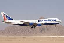 Side view of quadjet landing against a mountain backdrop.