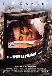 Film poster. On the side of the building is a large screen, showing a man laying his head on a pillow, eyes closed and smiling. Digital text above and below the screen state "LIVE" and "DAY 10,909", with the film's title right below it. Text at the top of the image includes the sole starring credit and text at the bottom includes the film's tagline and credits.