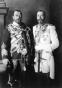 Two bearded men of identical height wear military dress uniforms emblazoned with medals and stand side-by-side