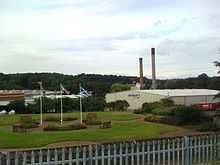 Large traditional paper manufacturer with two chimney stacks set in a mature landscape setting