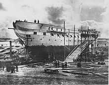 A photograph of a ship out of the water and under repair