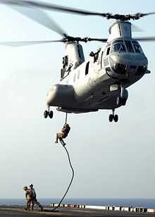 Marines descending from a helicopter with no equipment other than a rope.