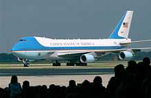 Presidential aircraft taxiing in front of silhouetted crowd.
