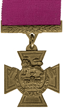 A medal in the shape of a cross hanging from a crimson red ribbon.