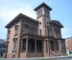 Low-angle photograph of Victoria Mansion in urban surroundings.