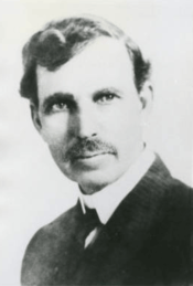 A black and white picture of a man in a suit with a large mustache