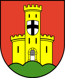 A shield with a red background, an orange castle in ruins, has a second shield of silver with a black cross.