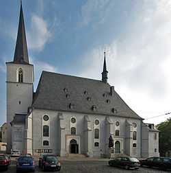 A pale grey church with white detail, dark roof, and a steeple