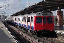 A photograph of a D Stock train departing West Ham on a westbound service.