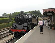 Steam locomotive (number 80136) with carriages at station platform.