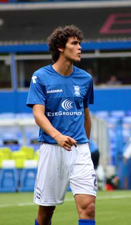 Tall curly-haired young man of athletic build wearing blue and white sports clothing