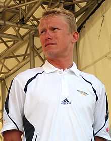 A man with blond hair wearing a white top