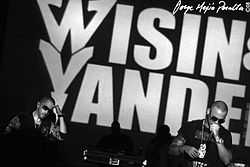 Two young men performing in front of large "Wisin & Yandel" background