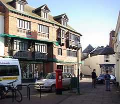 Street scene with buildings and shops. The three-storey building on the left has a sign saying The Courthouse.