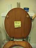 A yellow post-it note reading "You lose" stuck on the underside of a toilet.