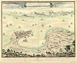 Coloured engraving of the Bay of Gibraltar as if seen from the top of a mountain to the north. Gibraltar is shown on the left, Algeciras on the right and the African coast in the background. The Spanish lines and camp are visible in the left foreground. Numerous ships are portrayed, some of them opening fire.