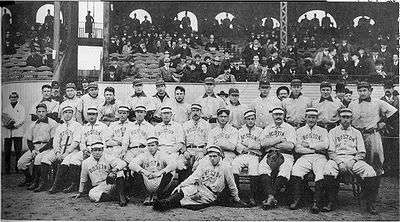 Two rows of men in white baseball uniforms. Those in the back row wear dark baseball  caps with "P" on them while the men in the front row wear white hats and have "BOSTON" on the chest of their uniforms.