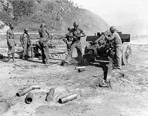 A crew of men on a howitzer as it fires