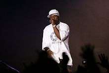 50 Cent, in white T-shirt and baseball cap, singing into a microphone