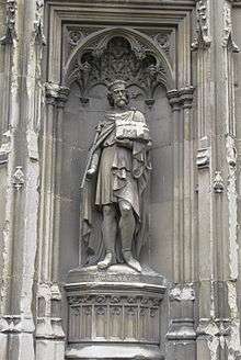 Stone statue of a crowned man holding a sceptre.