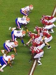 American football players on the line of scrimmage awaiting the snap.